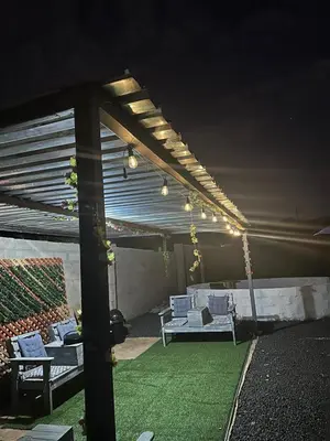 a patio with white couches and a green lawn at Rose's Lodge