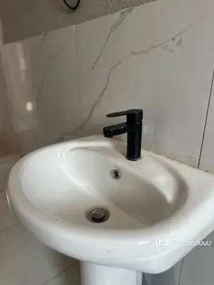 a white sink with a black faucet in a bathroom at Rose's Lodge