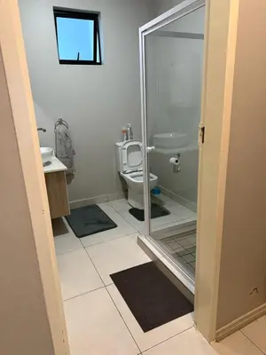 a bathroom with a toilet and a glass shower door at 1 bedroom cozy flat in Midrand