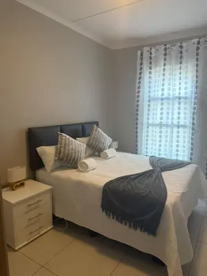 a bedroom with a large bed with a window at 1 bedroom cozy flat in Midrand
