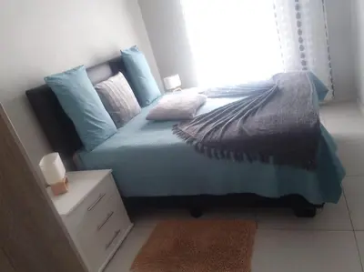 a bedroom with a bed with blue sheets and pillows at 1 bedroom cozy flat in Midrand