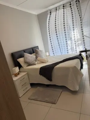a bedroom with a large bed and a window at 1 bedroom cozy flat in Midrand