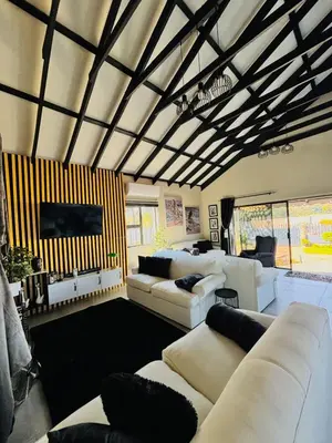 a living room with white couches and a large room at Calabash Executive Stay in Benoni