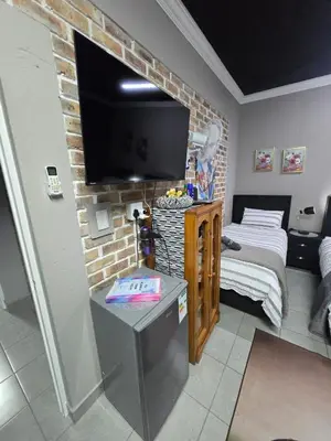 a small room with a bed and a flat screen tv at Calabash Executive Stay in Benoni