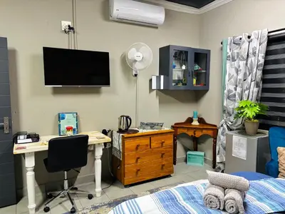 a bedroom with a desk and a bed with a television at Calabash Executive Stay in Benoni
