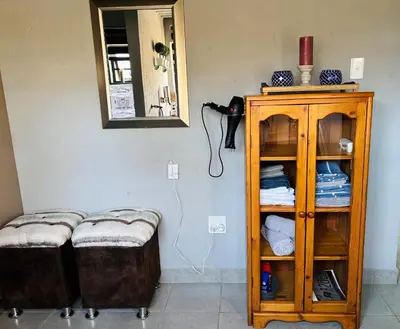 a room with two ottomans and a cabinet with a mirror at Calabash Executive Stay in Benoni