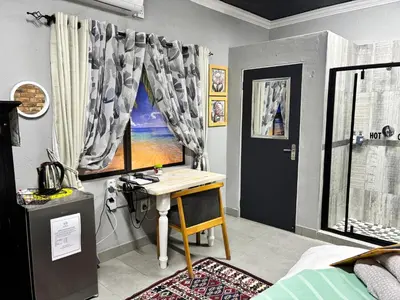 a bedroom with a desk and a bed with a window at Calabash Executive Stay in Benoni