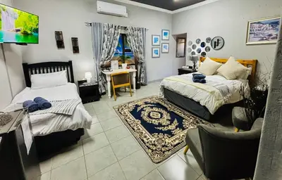 a bedroom with two beds and a tv in it at Calabash Executive Stay in Benoni