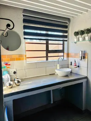 a bathroom counter with a sink and a window at Calabash Executive Stay in Benoni