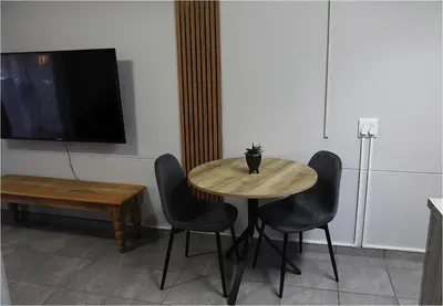 a table with four chairs and a tv on a wall at Casa Beato in Pretoria