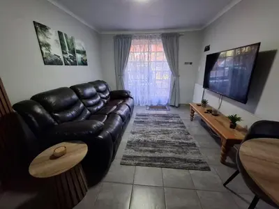 a living room with a leather couch and a flat screen tv at Casa Beato in Pretoria