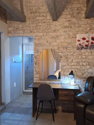 a desk with a mirror on a brick wall at Casa Beato in Pretoria