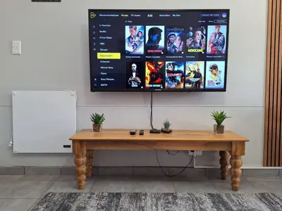 a television hanging on a wall with a wooden table at Casa Beato in Pretoria