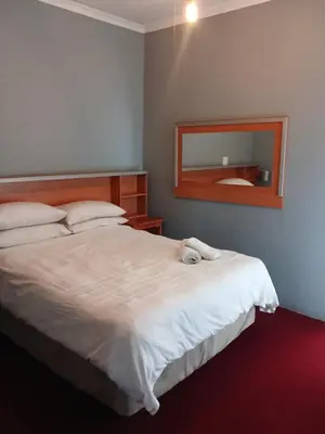 a bedroom with a large white bed with a mirror at Tushiya in Witbank