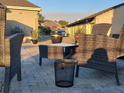 a patio with chairs and a table and a trash can at Tushiya in Witbank