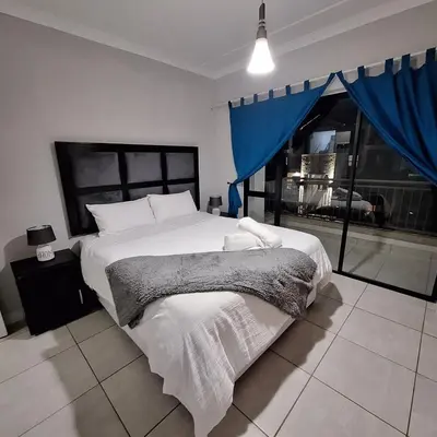 a bedroom with a large bed and a large window at The Bylde Crystal Lagoon Apartment in Pretoria