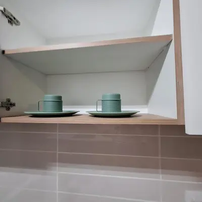 two cups and plates on a shelf in a kitchen at The Bylde Crystal Lagoon Apartment in Pretoria