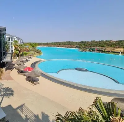a large swimming pool next to a beach at The Bylde Crystal Lagoon Apartment in Pretoria