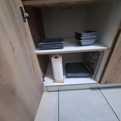 a cupboard with plates and a roll of paper towels at The Bylde Crystal Lagoon Apartment in Pretoria