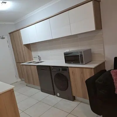 a kitchen with a microwave and a washing machine at The Bylde Crystal Lagoon Apartment in Pretoria