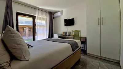 a bedroom with a bed and a desk and a window at 7 Heaven Boutique Hotel in Burgersfort