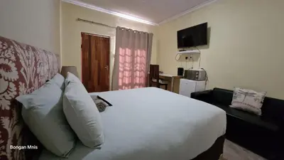 a bedroom with a white bed and a couch at 7 Heaven Boutique Hotel in Burgersfort