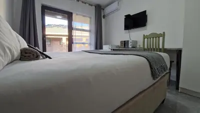 a bedroom with a bed with a television and a window at 7 Heaven Boutique Hotel in Burgersfort