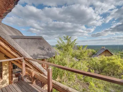 a balcony of a house with a thatch roof at 210 Zebula, 5-bedroom house & 1-bedroom cottage in Warmbaths