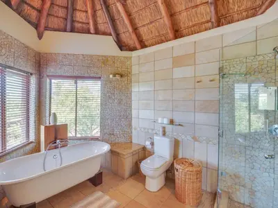 a large bathroom with a tub and a toilet at 210 Zebula, 5-bedroom house & 1-bedroom cottage in Warmbaths