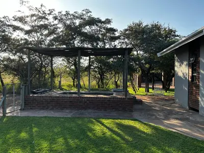 a gazebo in a yard next to a building at Dinokeng Bush Cabin in Hammanskraal