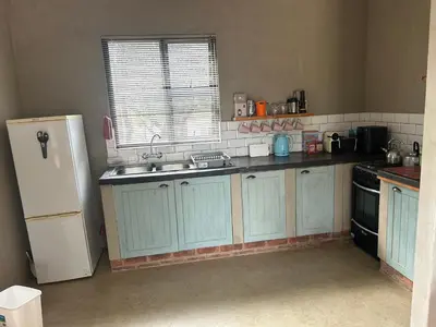 a kitchen with blue cabinets and a white refrigerator at Dinokeng Bush Cabin in Hammanskraal