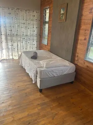 a bedroom with a bed with a cat laying on it at Dinokeng Bush Cabin in Hammanskraal