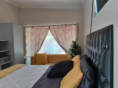a bedroom with a large bed and a window at Cozy in Centurion