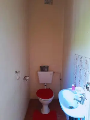a bathroom with a red toilet and a sink at Cozy in Centurion