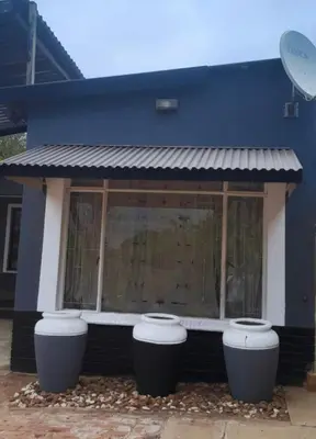 a blue building with three trash cans in front of it at Cozy in Centurion