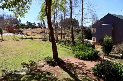 a tree in a yard next to a house at Tall Trees in Dullstroom