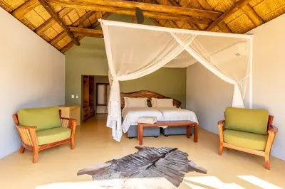a bedroom with a canopy bed and two chairs at Luxury & Wildlife Mlambo Lodge Mjejane in Hectorspruit