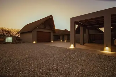 a large building with a large garage at night at Luxury & Wildlife Mlambo Lodge Mjejane in Hectorspruit
