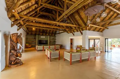 a large room with wooden ceilings and tables and chairs at Luxury & Wildlife Mlambo Lodge Mjejane in Hectorspruit