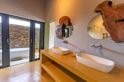 a bathroom with two sinks and two mirrors at Luxury & Wildlife Mlambo Lodge Mjejane in Hectorspruit