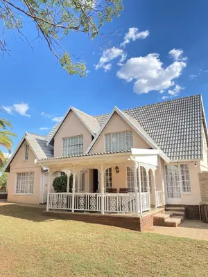 a large white house with a roof at Cosy Room steps from the lake- short term stay in Benoni