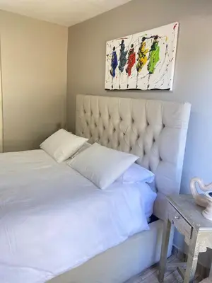 a bedroom with a white bed and a painting on the wall at Cosy Room steps from the lake- short term stay in Benoni