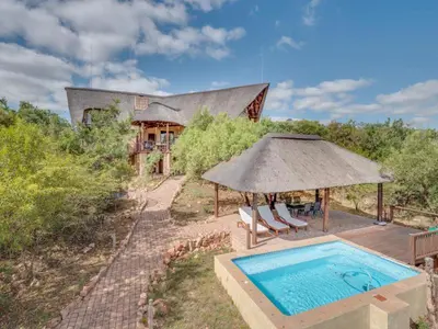 a house with a swimming pool and an umbrella at 210 Zebula, 5-bedroom villa in Warmbaths
