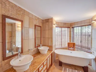a large bathroom with two sinks and two mirrors at 210 Zebula, 5-bedroom villa in Warmbaths