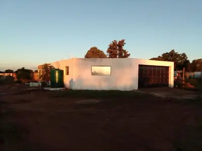 a small white house with a large garage at Mokoena Village guesthouse in Akasia
