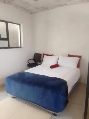 a bedroom with a large bed with a blue blanket on it at Mokoena Village guesthouse in Akasia