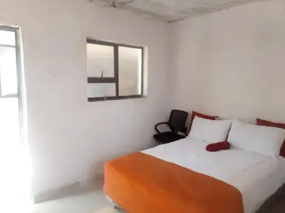 a bedroom with a bed with an orange blanket and a window at Mokoena Village guesthouse in Akasia