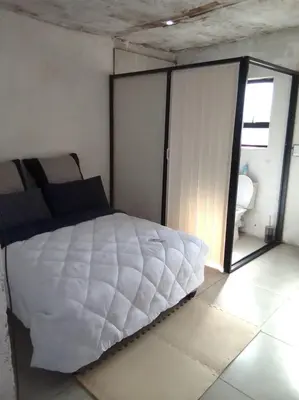 a bedroom with a large white bed with a sliding glass door at Mokoena Village guesthouse in Akasia