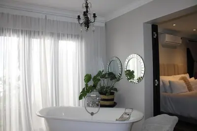 a bathroom with a tub and a bedroom with a bed at South Lawn Boutique Horse Hotel in Midrand