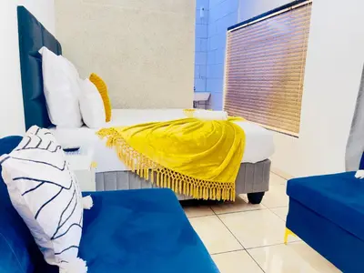 a bedroom with a bed with a yellow blanket on it at Genza Guesthouse in Pretoria in Pretoria